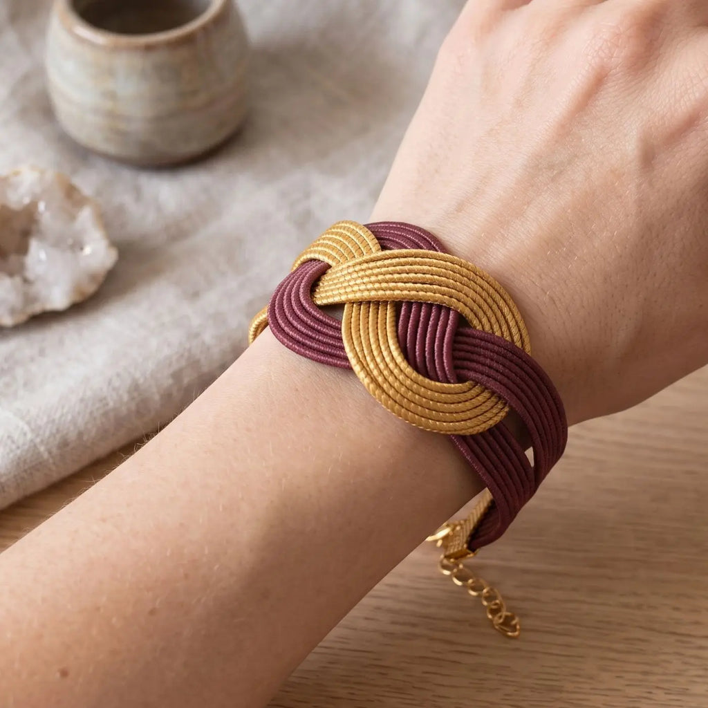 Détail du tressage entrelacé doré et bordeaux du Bracelet Éternelle
